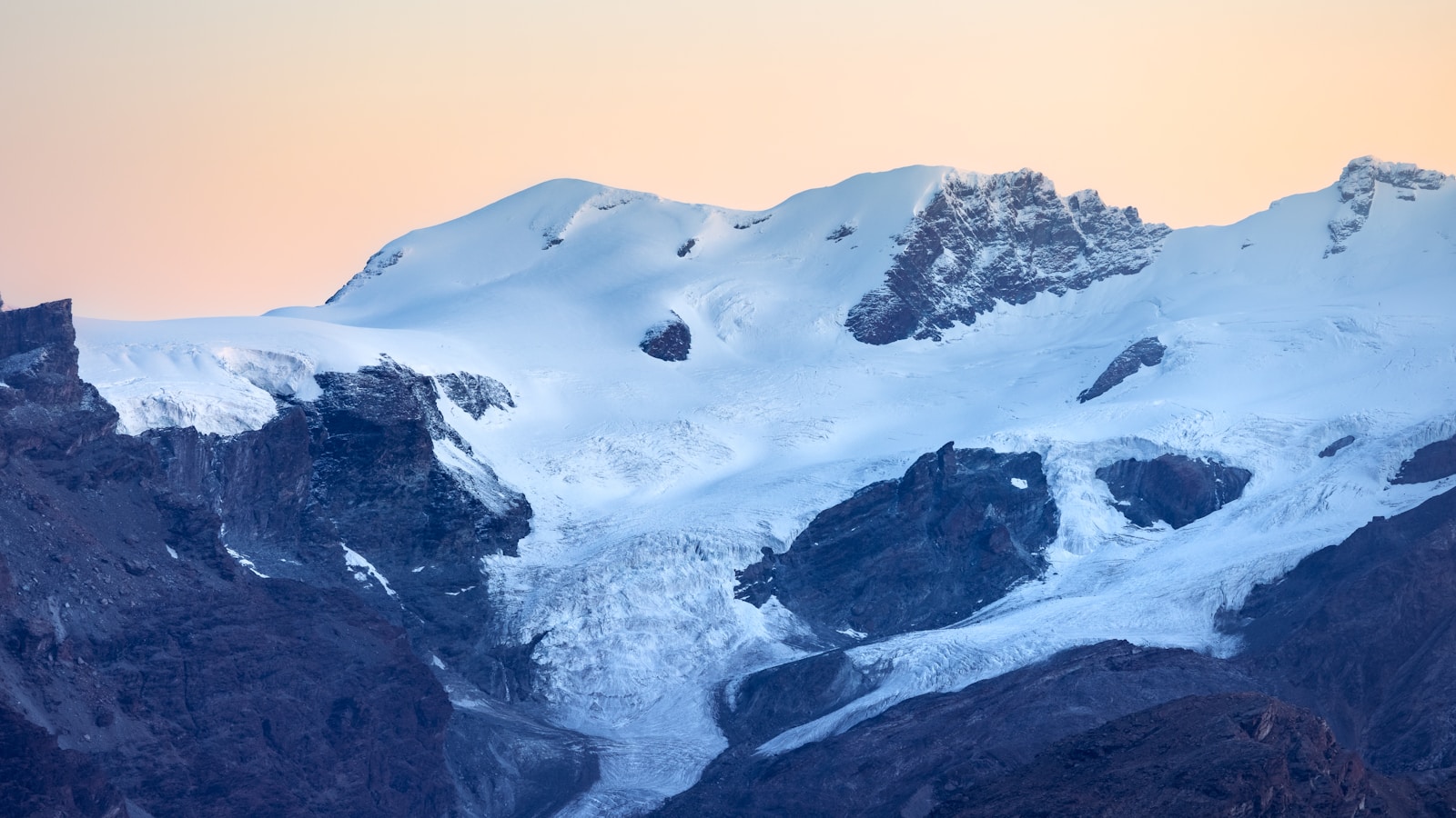 A snow covered mountain with a bird flying over it
